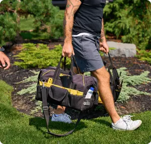 Technician walking with a tool bag toward a customer’s home.