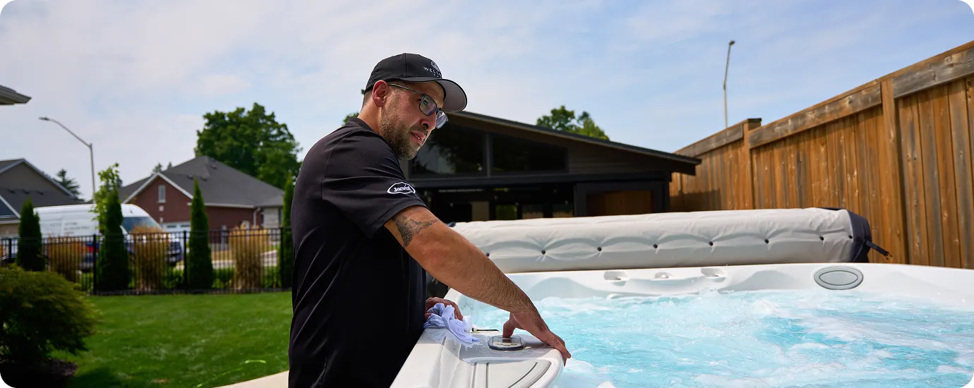 Technician wiping the edge of a hot tub after completing a repair.